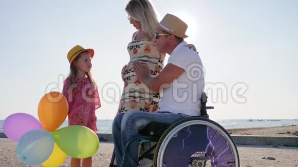 大肚子的快乐妈妈和轮椅上的女儿和丈夫交流怀孕残疾男人视频的预览图