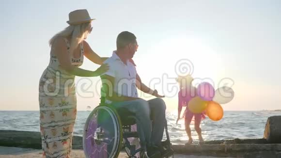 在海边快乐休息妻子和女儿都会带着五颜六色的气球一家人带着孩子视频的预览图