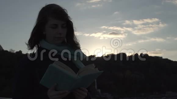 年轻的女士在日落时看书视频的预览图