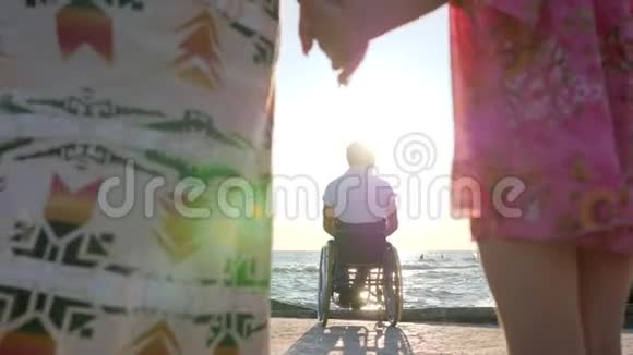 母亲和女儿在父亲坐轮椅的背景下保持双手视频的预览图