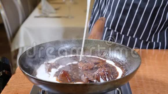 在餐馆做饭在工作的饼干职业厨师手套将奶油倒入平底锅与肝脏慢动作视频的预览图