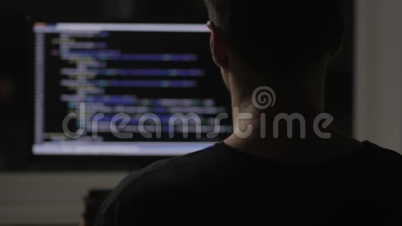 在黑暗的房间里从后面编程并在电脑显示器上编程代码视频的预览图