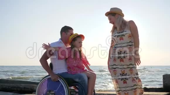 小女孩坐在双手瘫痪的爸爸坐在轮椅上伸出双臂背光怀孕的妻子有孩子视频的预览图