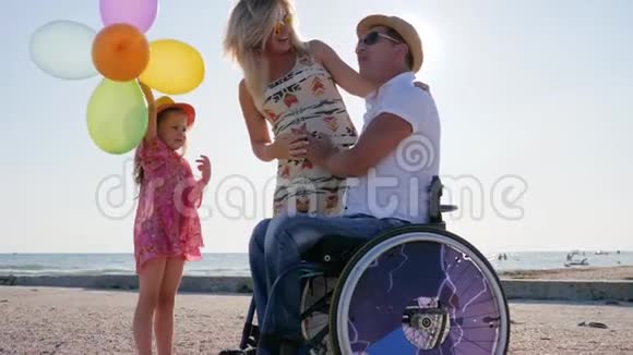 夏天小女孩在沙滩上坐轮椅听爸爸妈妈的话视频的预览图
