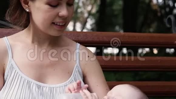 母亲在公园里给婴儿喂奶奶瓶中的婴儿奶视频的预览图