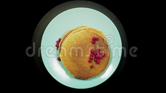 盘子上有浆果的煎饼在黑色背景上旋转俯视视频的预览图