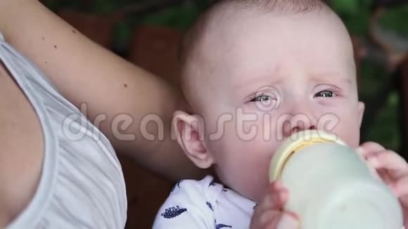 母亲在公园里给婴儿喂奶奶瓶中的婴儿奶视频的预览图