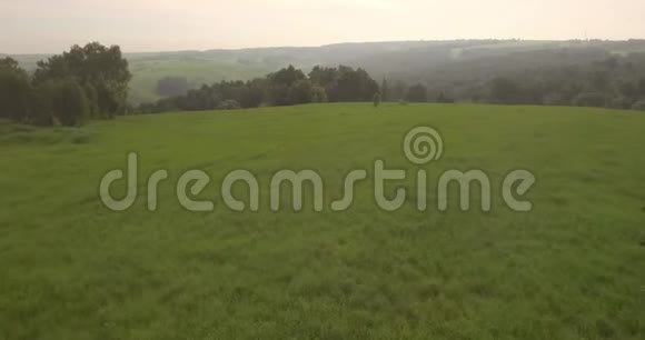 鸟瞰傍晚时间在山上飞过一片绿草4K视频的预览图