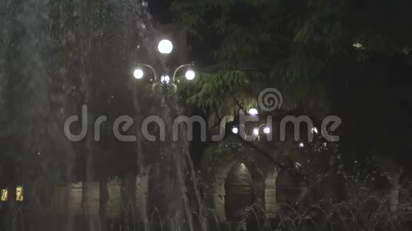 喷泉在夜间对着照明的街灯在空中喷射水射流视频的预览图