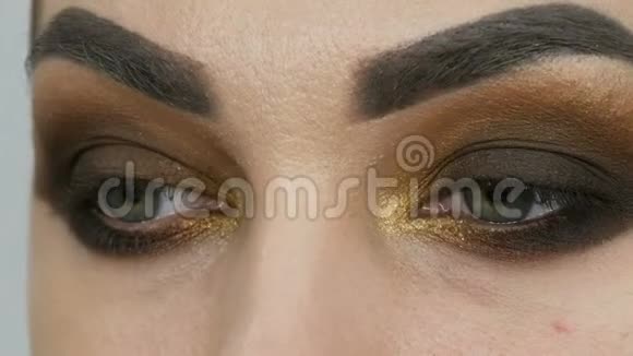 专业的化妆师让一个绿色的眼睛闭起来的漂亮模特的浓妆浓抹的棕色眼睛视频的预览图
