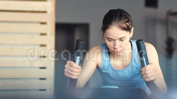 健身房里漂亮的女人用自行车锻炼腿部做有氧训练视频的预览图
