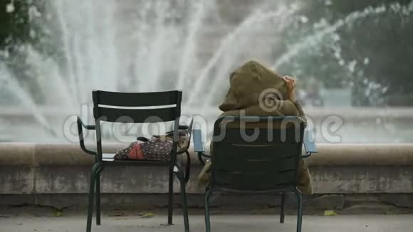 女人坐在喷泉附近的椅子上在城市里放松自由活动视频的预览图