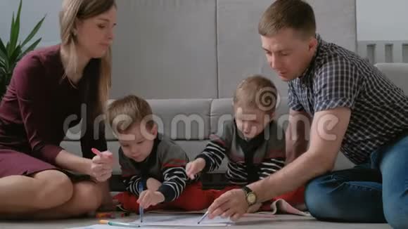一家人的妈妈爸爸和两个双胞胎兄弟一起画记号摸着笔坐在地板上视频的预览图