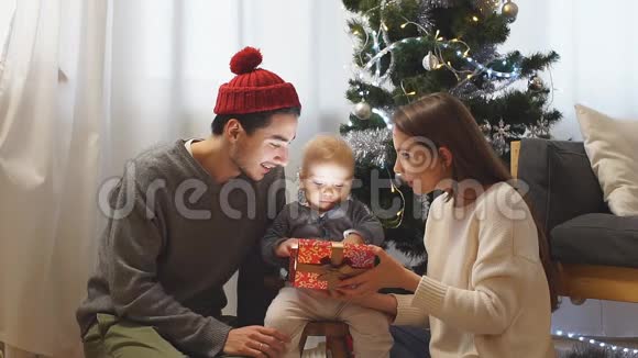 父母和孩子在家里打开圣诞礼物视频的预览图