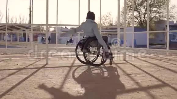 在傍晚秋季或春季坐轮椅的残疾青年妇女在该地区的海滩上休息视频的预览图