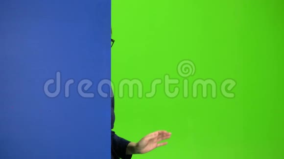 女孩从一块蓝色的木板后面窥视并伸出大拇指绿色屏幕视频的预览图