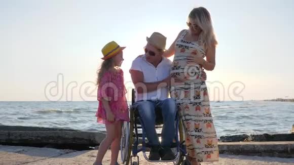 轮椅上残疾小女儿摩擦母亲腹部孕妇残疾男子幸福家庭视频的预览图