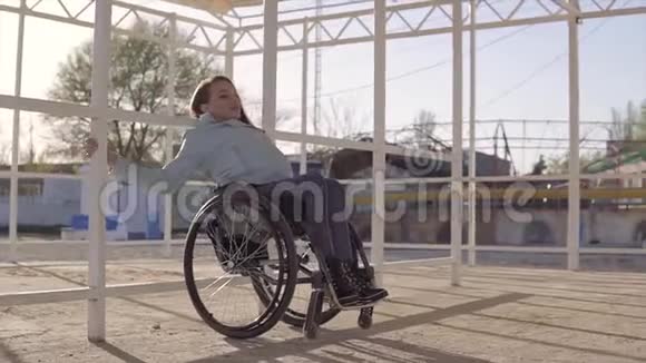 在傍晚秋季或春季坐轮椅的残疾青年妇女在该地区的海滩上休息视频的预览图