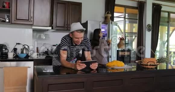 夫妻使用平板电脑年轻男女在厨房工作室聊天在线饮料果汁现代家庭内部视频的预览图