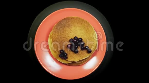 盘子上有浆果的煎饼在黑色背景上旋转俯视视频的预览图