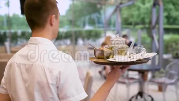 后景服务员端茶盘给坐在餐厅的家人视频的预览图