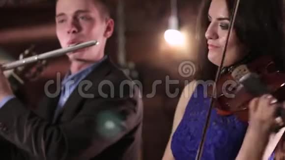 两个人演奏音乐一个穿着蓝色连衣裙的漂亮黑发女子正在拉小提琴而那个穿夹克衫的家伙视频的预览图