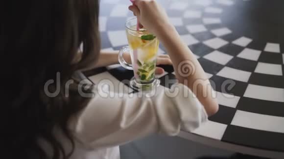 从后面看女孩用小管搅拌柠檬水4K视频的预览图