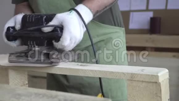 主人戴着白色手套和绿色围裙用工具打磨天然木材制成的制品及其制品视频的预览图