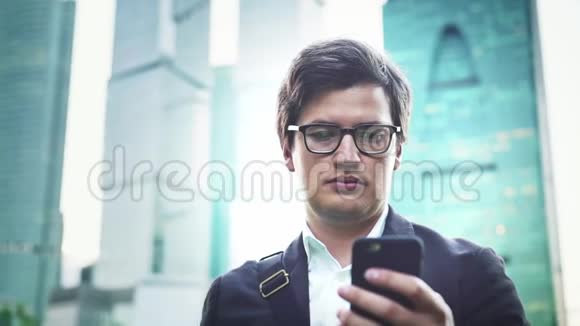 穿着西装的英俊商人在莫斯科的智能手机屏幕上视频的预览图