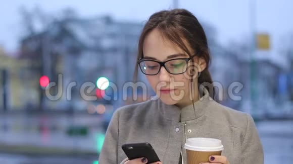 年轻女性在户外喝咖啡时使用智能手机视频的预览图