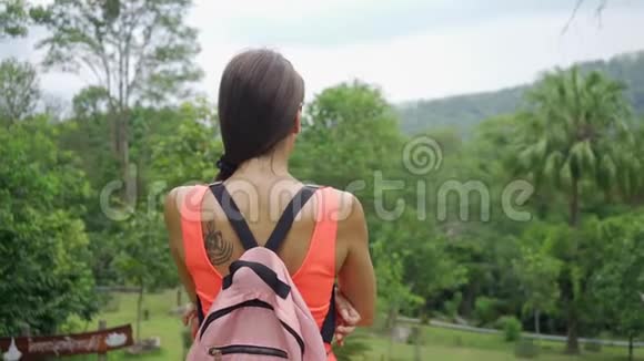 美丽的热带雨林带着一位年轻的女旅行者在进入泰国森林的路上女人在雨林里散步视频的预览图