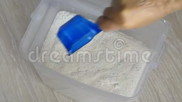 用蓝色塑料铲子把透明手套从盒子里拿出一些洗衣粉视频的预览图