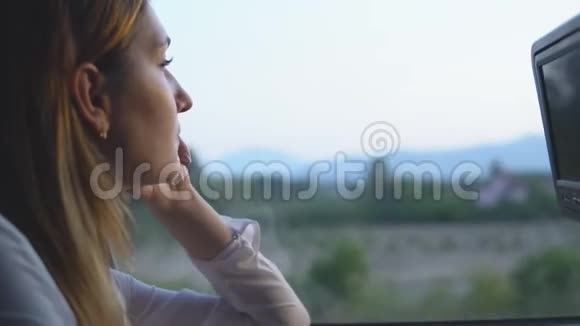 漂亮的女人望着窗外欣赏着美丽的大自然视频的预览图