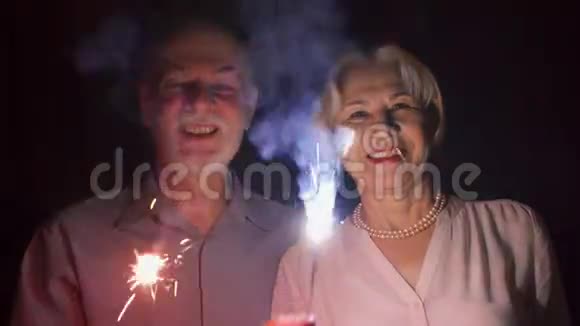 一对有火花的老夫妇在庆祝幸福的一家人举着孟加拉灯享受圣诞前夜视频的预览图