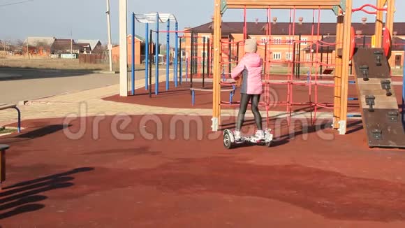 红发女孩骑着一辆自平衡的滑板车操场上的孩子们视频的预览图