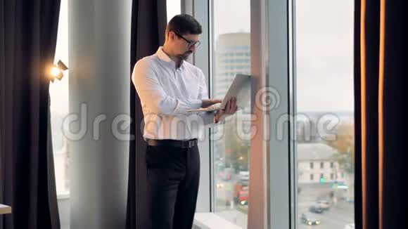 一个商人站在高高的窗户和类型附近视频的预览图