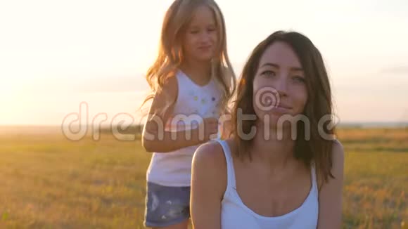 家庭娱乐妈妈和她女儿玩女儿坐在母亲身边走进夕阳一起快乐视频的预览图