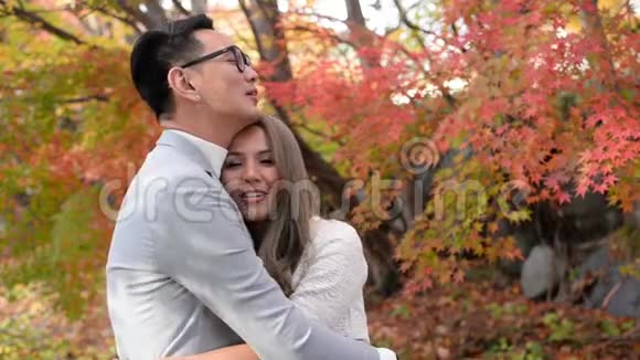 幸福的情侣拥抱在红枫秋的场景中视频的预览图