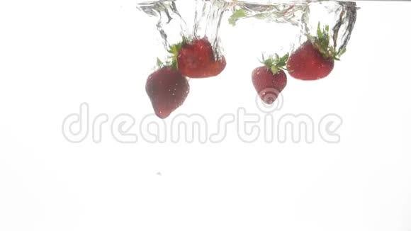 特写慢镜头视频新鲜成熟的草莓和绿色薄荷叶在冰冷清澈的水中飘落和飞溅视频的预览图