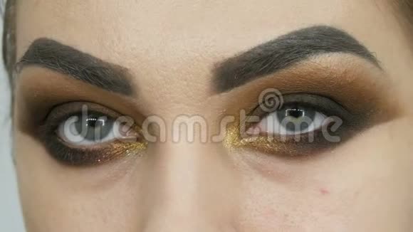 专业的化妆师让一个绿色的眼睛闭起来的漂亮模特的浓妆浓抹的棕色眼睛视频的预览图