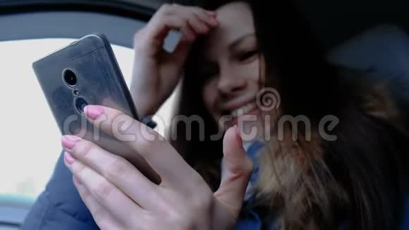 有手机的女人在车里年轻漂亮的黑发女人看着手机里的东西笑了起来视频的预览图