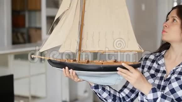 一位快乐的年轻女子手里拿着一艘帆船的模型视频的预览图