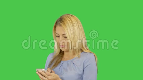 年轻的微笑美丽的女人在智能手机上输入信息隔离在透明的绿色屏幕背景上阿尔法视频的预览图