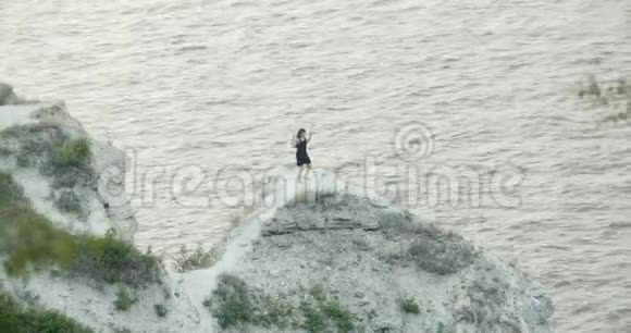 穿着黑衣的年轻女子在海边的悬崖上跳舞视频的预览图