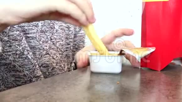 一个男孩在一家餐馆吃快餐把薯条放进一个带有酱汁的塑料一次性容器里关上视频的预览图