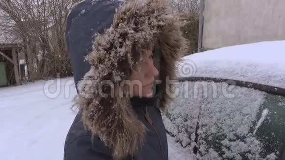女人用刷子清除车窗外的积雪视频的预览图