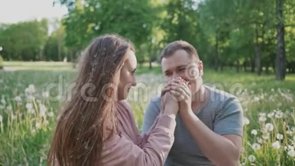 一对浪漫的情侣在夏天的白蒲公英的空地上一个年轻人亲吻他女朋友手快乐视频的预览图