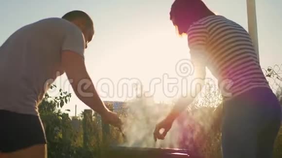 快乐夫妇在烧烤架上煮香肠一对夫妇在野餐时边吃边喝快乐的人视频的预览图