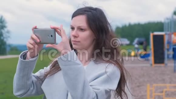 年轻女子在操场上用手机拍摄照片和视频视频的预览图