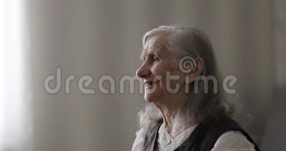 快乐的老妇人一头白发在蛋糕上吹蜡烛视频的预览图